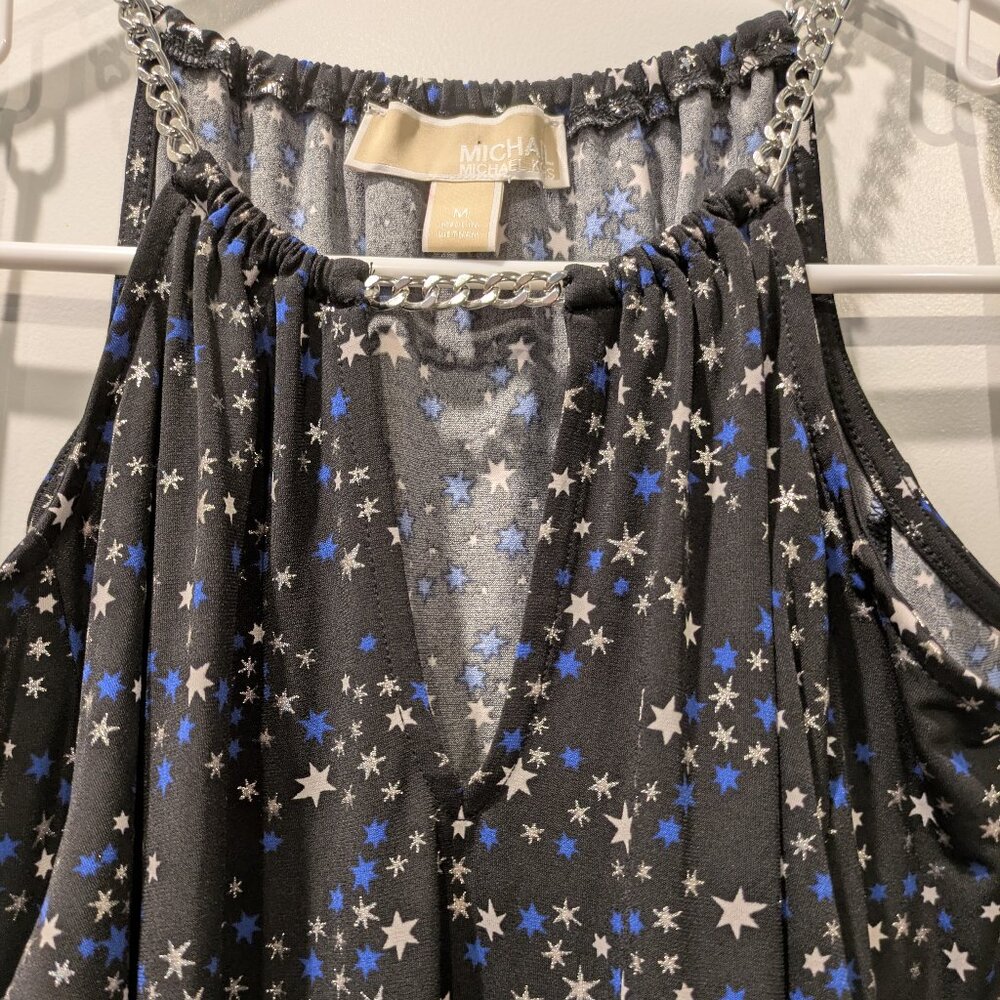 Michael Kors black top with white and blue star patterns and a silver chain on t